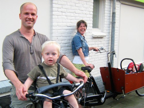 A young family prepare for a journey. Father and toddler on one bike, mother rides a 'bakfiets' with the baby in.