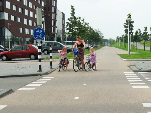 A mother and her two daughters set off at the traffic lights.