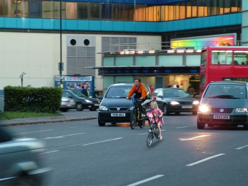 A photograph of a young girl on a bike in the Netherlands, juxtaposed with one of London's most deadly road junctions.