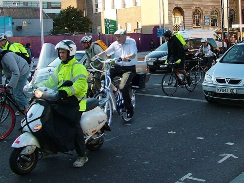 A photo of an elderly man calmly riding a bike in the Netherlands, juxtaposed with heavy traffic in London.