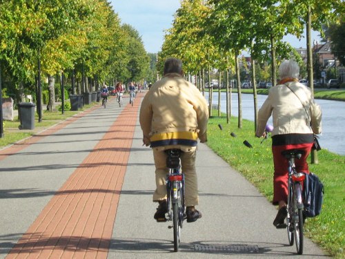An older couple ride their bikes along a bicycle road in the Netherlands
