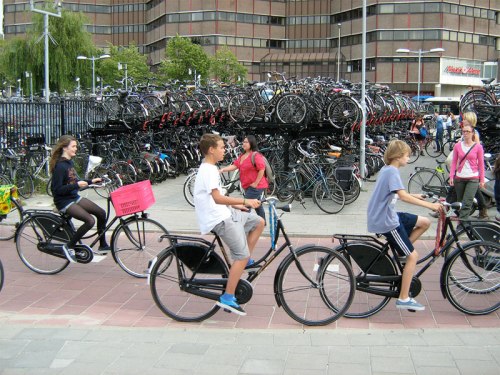 Three Dutch kids ride their bikes past one of the many bike parking areas in Utrecht.
