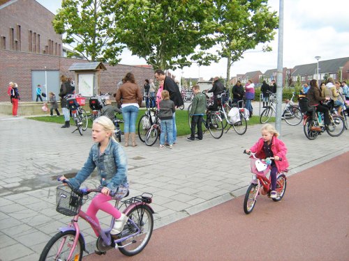 Two young girls ride bikes home from school in the Netherlands, safely on the cycle path, away from motor vehicles.