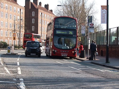 A photo of a bus pulled into a bus stop, which blocks the cycle lane but keeps general traffic lane clear.