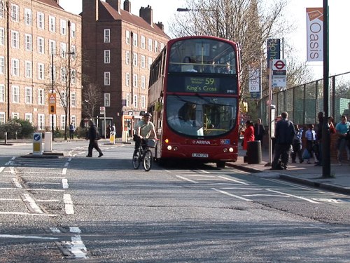A photo of bus blocking a cycle lane, and a bike rider overtaking the bus which is about to pull out.