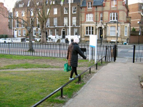 A middle-aged woman carrying shopping steps over the fence.