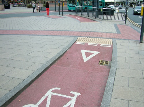 A photo of a cycle track which runs beside a pedestrian crossing. The cycle track gives way then disappears, only to re-appear after the pedestrian waiting area
