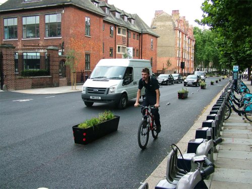 A man riding a bike along the Royal College Street cycle lane. He is well away from the kerb.