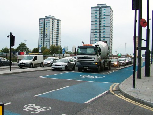 A cement mixer waits to turn left at a Barclays Cycle Superhighway junction. It will get a green light at the same time as people on bikes.