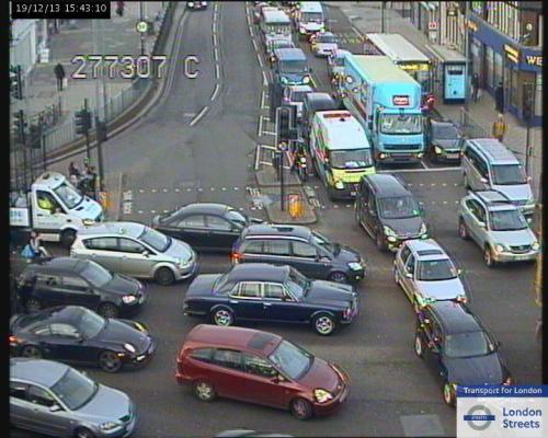 A still from one of TfL's traffic-cams, showing traffic at a crossroads. One road has three lanes, the other has five. The traffic flows are blocking each other, leading to gridlock.