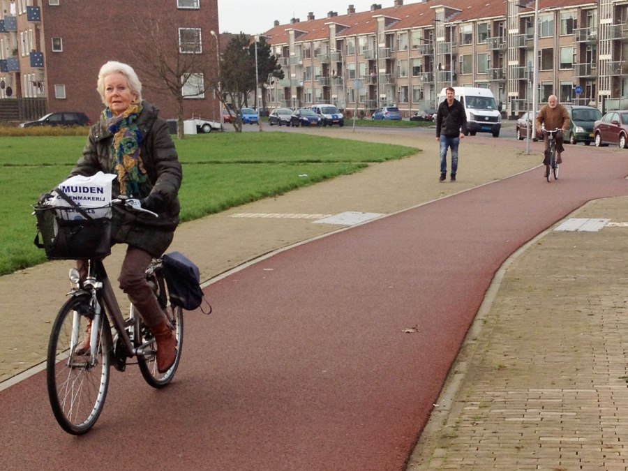 A woman cycles on a smooth, wide cycleway, separated from both the footway and the carriageway.