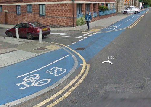 A junction on the Cable Street cycleway in London. The cycleway has priority, but everything suggests otherwise: the kerb and yellow lines cut across the cycleway, creating confusion.