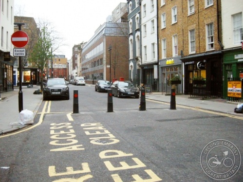 Four bollards placed across Warren Street in London prevent motor vehicles from being driven through, but allows cycles.