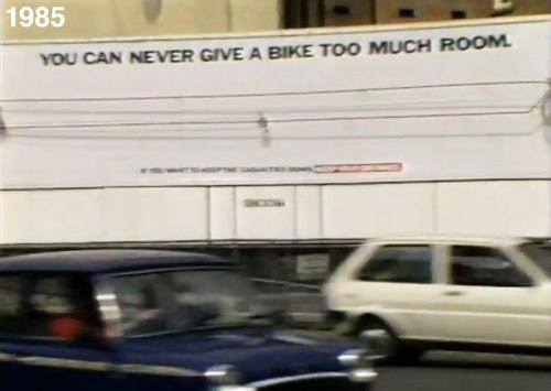 A large billboard with the words 'You can never give a cyclist too much room. If you want to keep casualties down, keep your distance'. It has a hugely stretched bike on it. Cars speed past in the foreground.